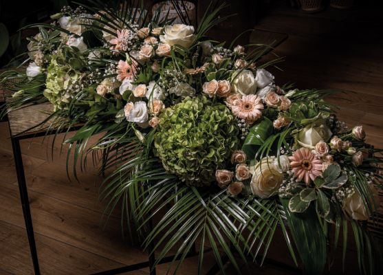 Grande gerbe funéraire élégante avec des roses blanches, des hortensias verts, des gerberas roses et un feuillage raffiné, conçue dans le Pays de Gex